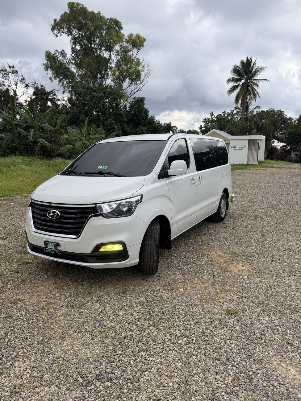 White Hyundai H-1 passenger van, the vehicle used for private transfers, parked outside on a gravel driveway